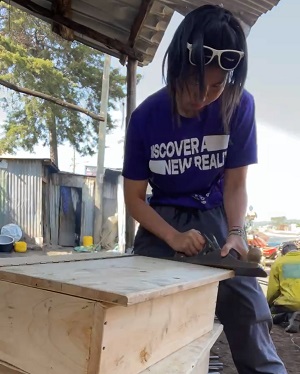 Cherie using a saw to help build a table