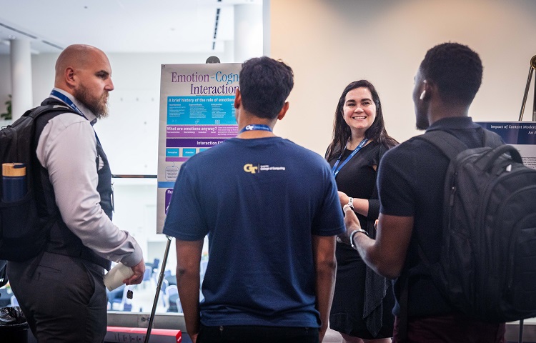 Someone presenting their poster to 3 other people