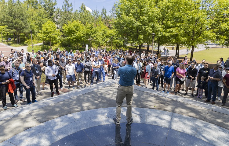 David Joyner, with his back to us, holding a megaphone and speaking to a large crowd on campus