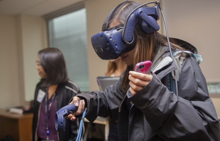 Person wearing a VR headset and holding a controller and a smartphone