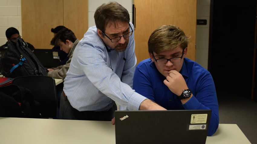 Ben Schepens standing next to a student and pointing at the students laptop screen