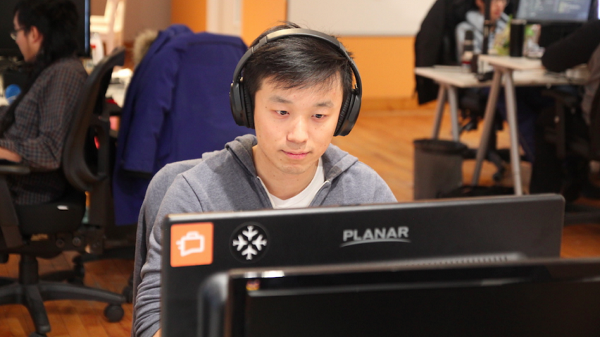 Henry Shi sitting in front of a computer screen wearing headphones