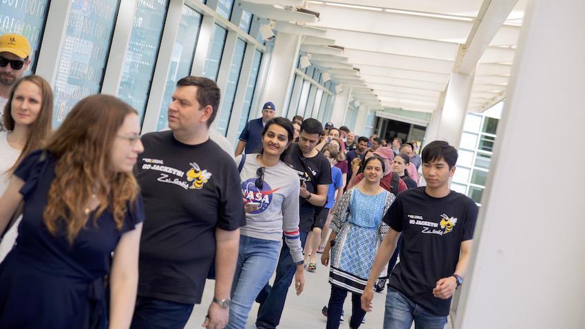 OMSCS graduates walking along the bridge between CCB and Klaus buildings on campus