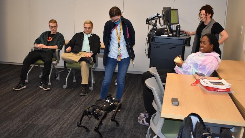 5 people looking at a robot
