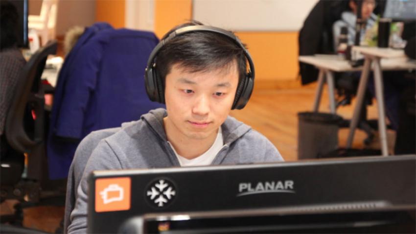 Henry Shi sitting in front of a computer screen wearing headphones