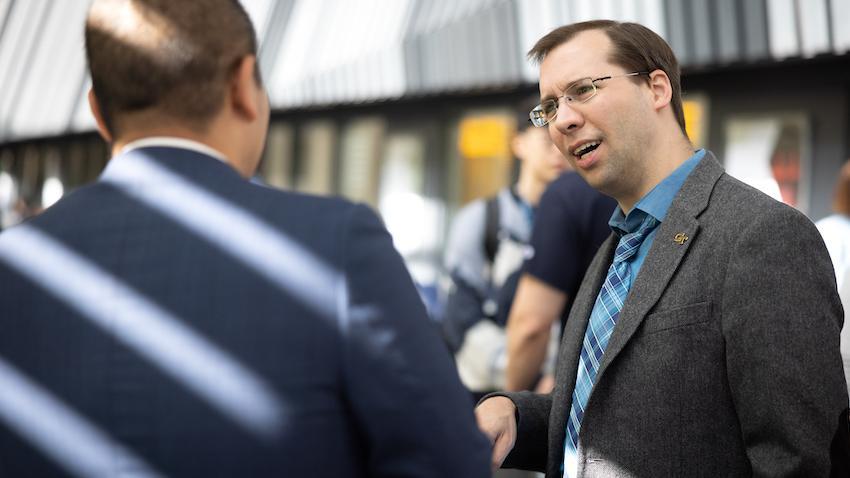 David Joyner in a suit and tie talking to someone at the OMSCS Conference