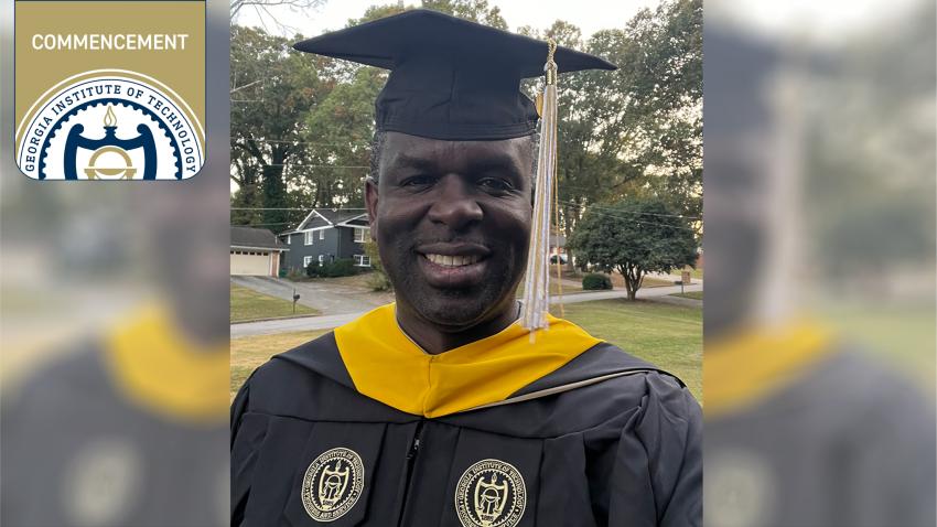 Michael Washington standing outside in graduation cap and gown