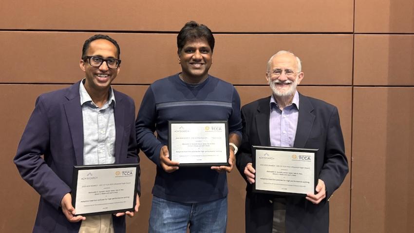 Moin holding his award and standing with 2 other honorees