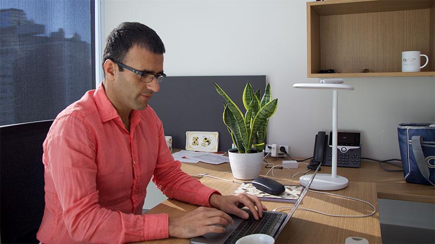 Person sitting at a desk in an office typing on a laptop