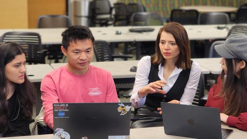 4 people in a classroom sitting around laptops