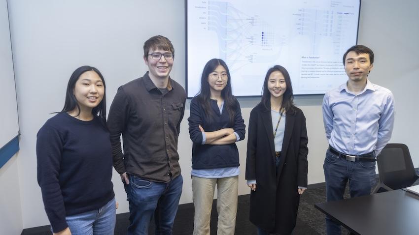 Five researchers standing in front of a projector screen