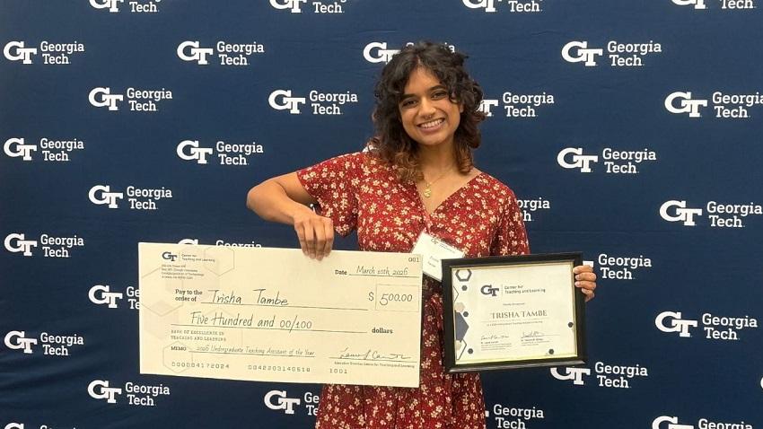 Woman holding an award and a check for $500